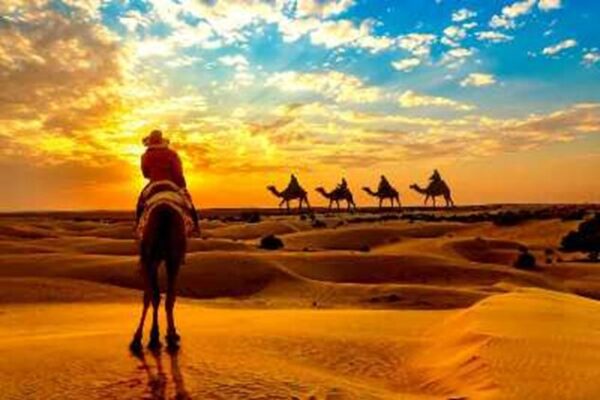 Tourists on camel travelling over desert